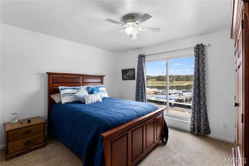 Bedroom featuring light colored carpet, a water view, and ceiling fan — 10107 Greenbriar Court, Foristell, MO 63348
