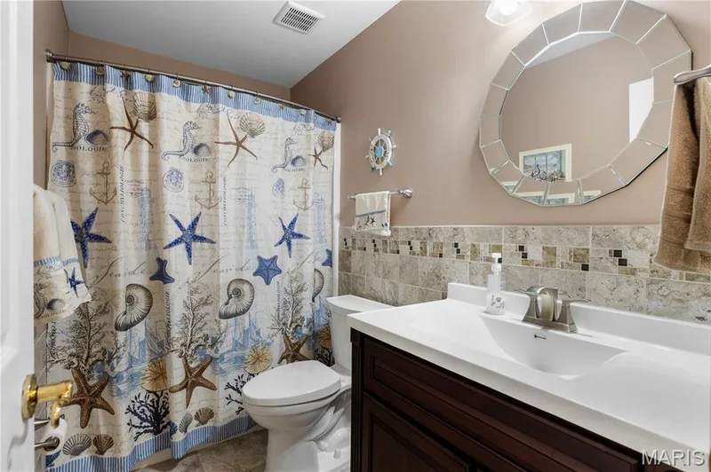 Bathroom featuring vanity, curtained shower, and tile walls — 10107 Greenbriar Court, Foristell, MO 63348