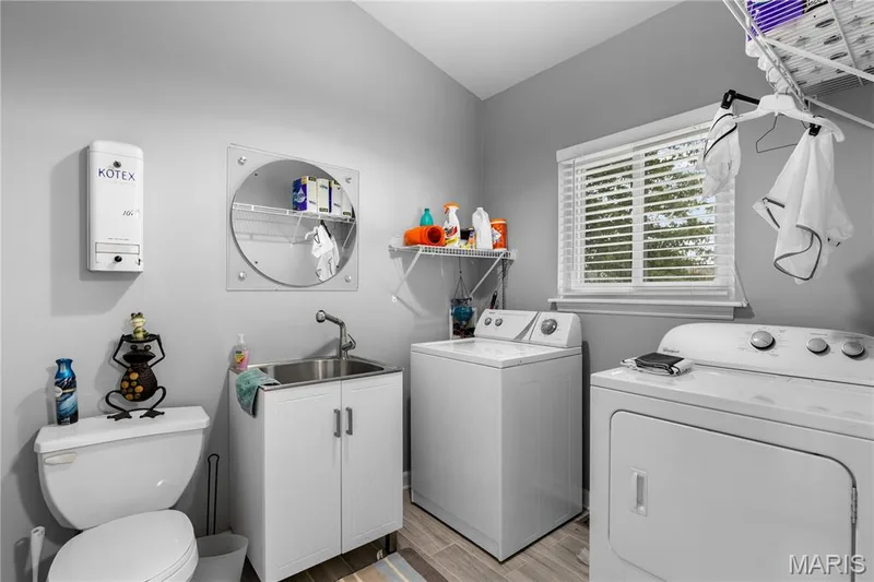 Bathroom featuring wood finish floors, washer and dryer, and vanity — 10107 Greenbriar Court, Foristell, MO 63348