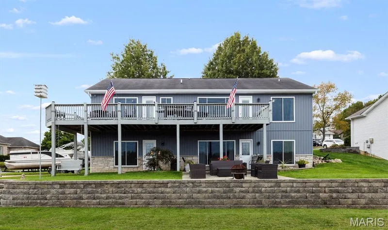 Rear view of house with a patio, stone siding, a wooden deck, and outdoor lounge area — 10107 Greenbriar Court, Foristell, MO 63348