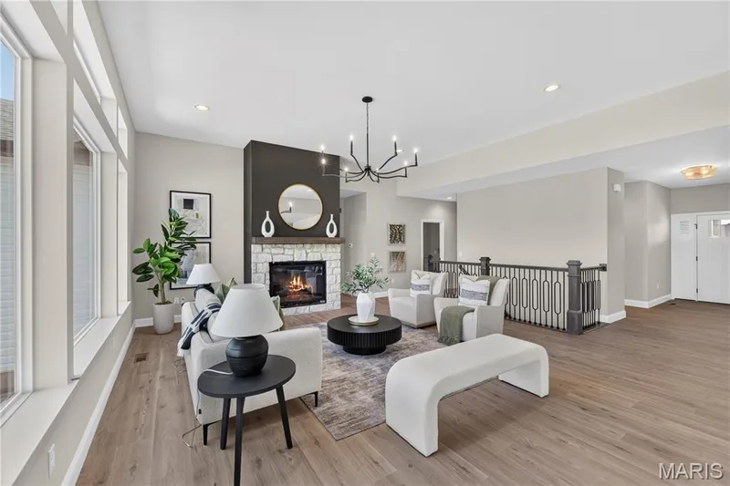 Spacious Great area featuring large windows, wood-finish flooring, a stone fireplace with a dark accent wall, and 11 FT ceilings — 126 Royal Troon Drive, Dardenne Prairie, MO 63368