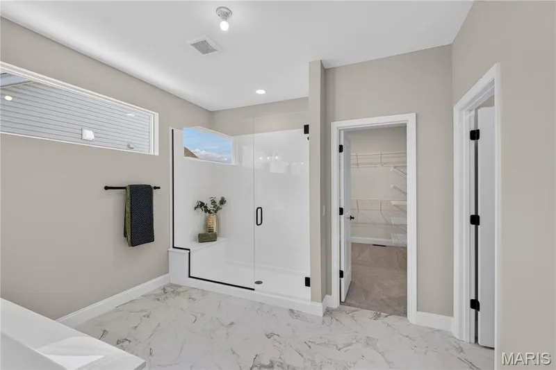 Owner's bathroom featuring a glass-enclosed shower with a built-in bench, transom windows, and large format marble-look floor tiling — 126 Royal Troon Drive, Dardenne Prairie, MO 63368