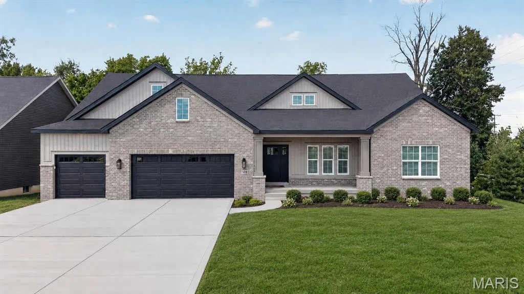 Light-colored brick exterior featuring dark gray garage doors, a covered entry, and a symmetrical front landscape — 128 Royal Troon Drive, Dardenne Prairie, MO 63368
