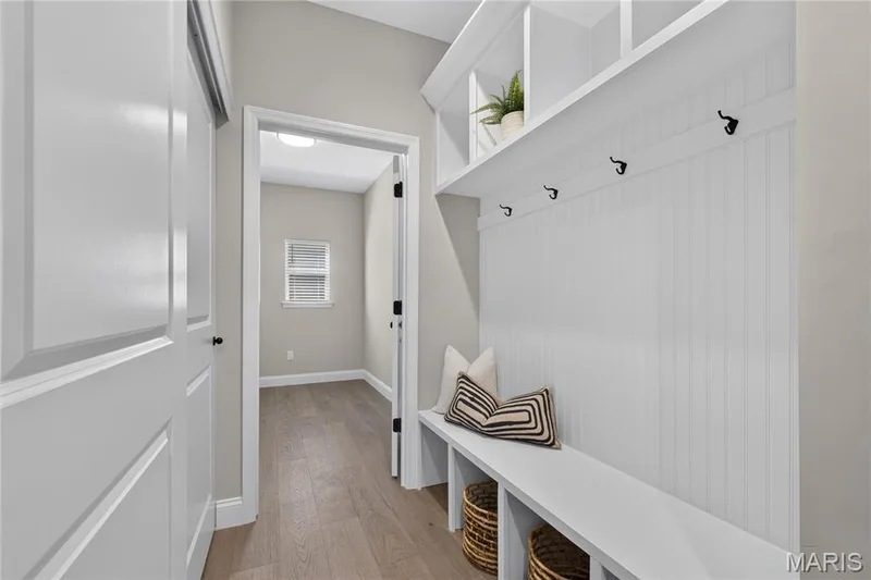 Built-in storage bench with open shelving, wall hooks, and beadboard paneling — 128 Royal Troon Drive, Dardenne Prairie, MO 63368