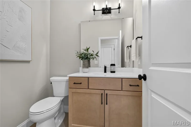 Powder bath featuring light wood-finish vanity with dark hardware, white countertop, and integrated rectangular sink — 128 Royal Troon Drive, Dardenne Prairie, MO 63368