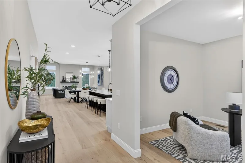 Open-concept living area featuring light wood-finish flooring, recessed lighting, a kitchen island with seating, a dining area, and a living room with a fireplace — 366 Strawberry Grove Drive, O'Fallon, MO 63376