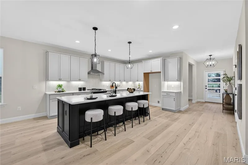 Open-concept kitchen with a large island featuring a white countertop and dark cabinetry — 366 Strawberry Grove Drive, O'Fallon, MO 63376