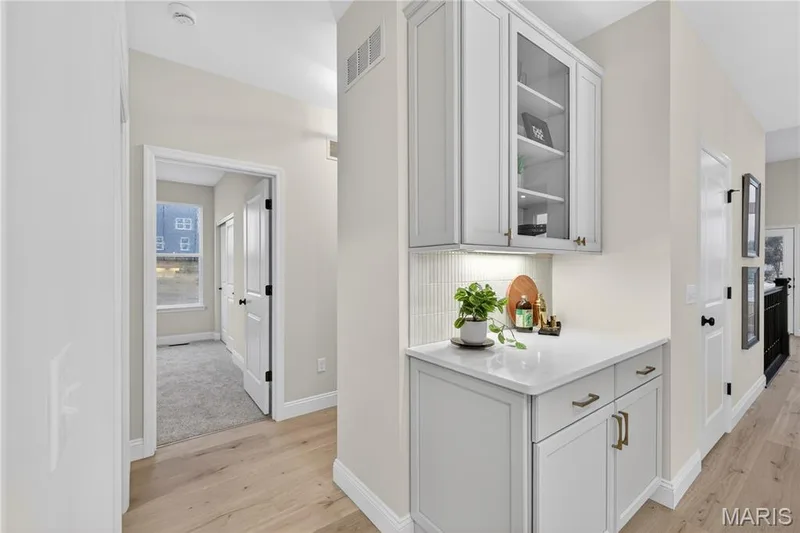 Built-in white cabinetry with glass-front uppers, a light-toned countertop, and a vertical subway tile backsplash — 366 Strawberry Grove Drive, O'Fallon, MO 63376