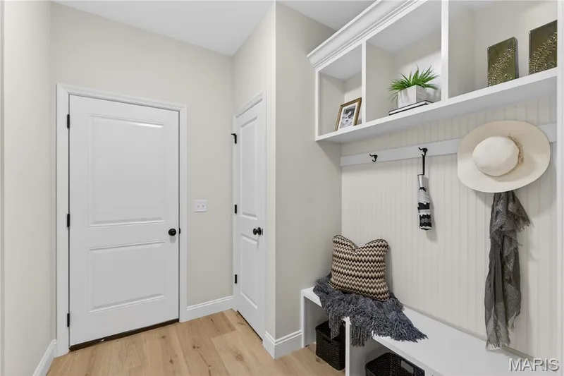 Mudroom featuring built-in white cabinetry with open shelving, integrated bench seating, and beadboard paneling — 366 Strawberry Grove Drive, O'Fallon, MO 63376