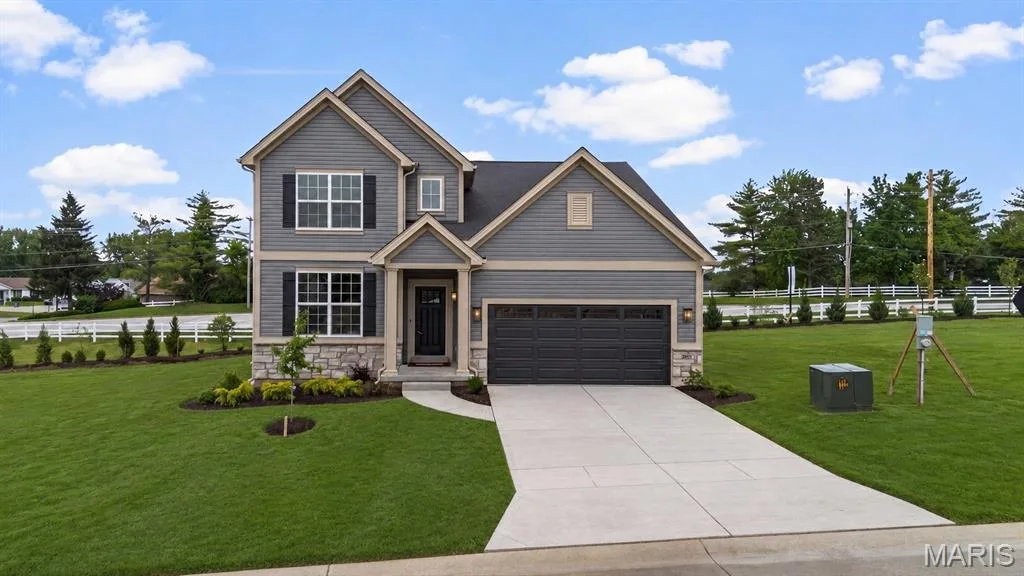 1.5 story residence featuring grey siding with stone accents, a two-car garage, and a concrete driveway — 369 Strawberry Grove Drive, O'Fallon, MO 63376