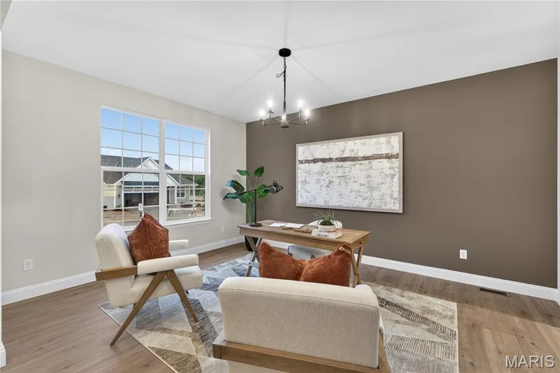 Versatile interior space featuring wood-finish flooring, a contemporary chandelier, and a large window with grid pattern — 369 Strawberry Grove Drive, O'Fallon, MO 63376