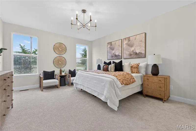 Spacious bedroom featuring light-toned walls and plush carpeting, illuminated by a contemporary chandelier — 369 Strawberry Grove Drive, O'Fallon, MO 63376
