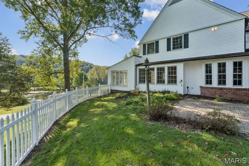 White picket fence enclosing a grassed area, stone paver patio, multiple windows, and a brick foundation — 2333 Ossenfort Road, Wildwood, MO 63038