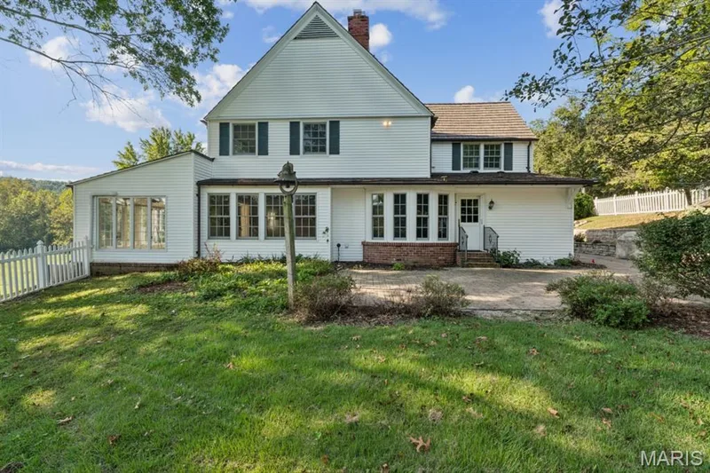 Expansive rear facade featuring multiple windows, a sunroom extension, and a white picket fence — 2333 Ossenfort Road, Wildwood, MO 63038