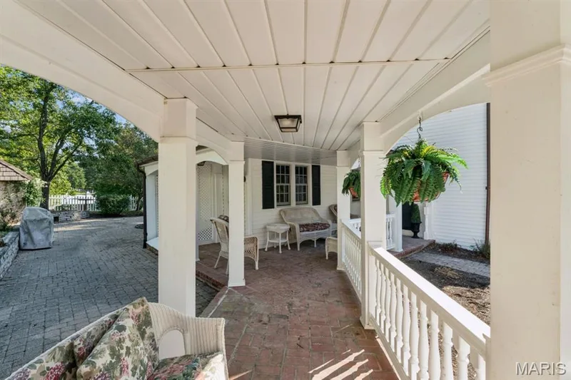 Covered porch featuring a brick-finish floor, white baluster railing, and white column supports — 2333 Ossenfort Road, Wildwood, MO 63038