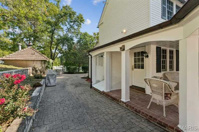 Brick paver driveway, covered patio with brick flooring, white lattice detailing, and a shingled outbuilding — 2333 Ossenfort Road, Wildwood, MO 63038