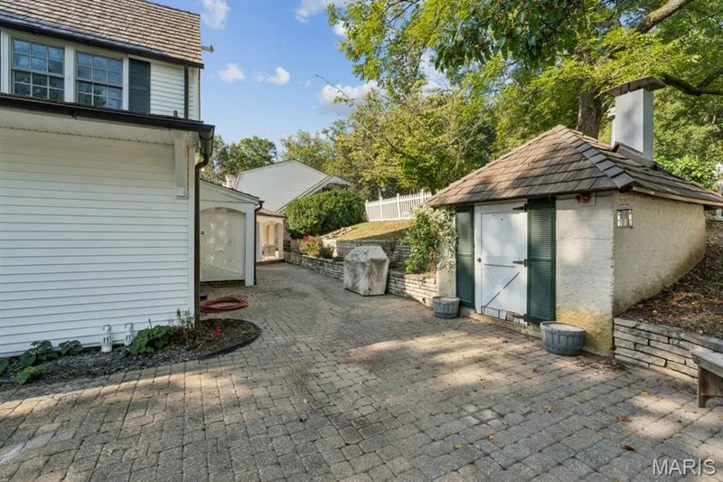 Paver driveway leading to an outbuilding with a shingled roof, stucco finish, and stone retaining walls — 2333 Ossenfort Road, Wildwood, MO 63038