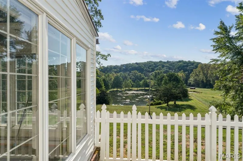 White picket fence, multi-pane windows, siding exterior, expansive green landscape, distant pond — 2333 Ossenfort Road, Wildwood, MO 63038