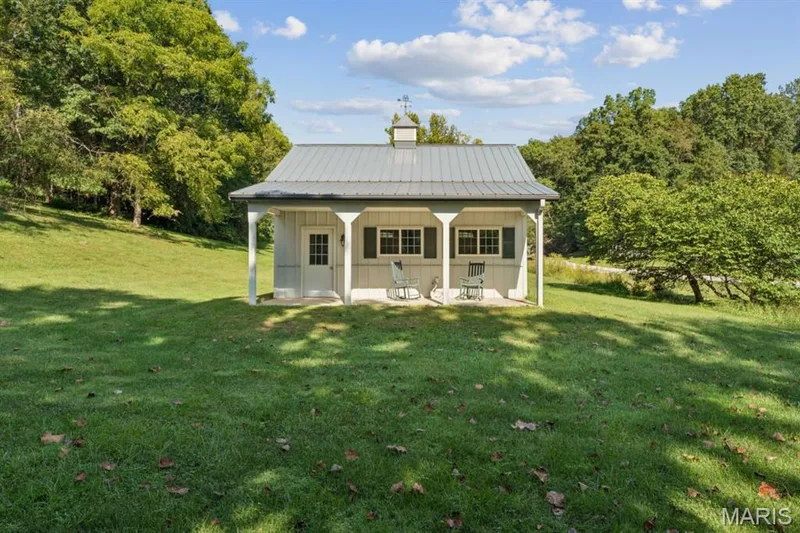 White exterior structure with a covered porch, metal roof, cupola, and dark window shutters — 2333 Ossenfort Road, Wildwood, MO 63038