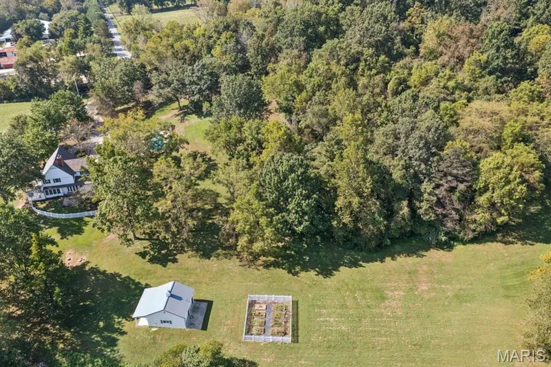 Expansive green landscape featuring a detached structure, fenced garden beds, and mature trees — 2333 Ossenfort Road, Wildwood, MO 63038
