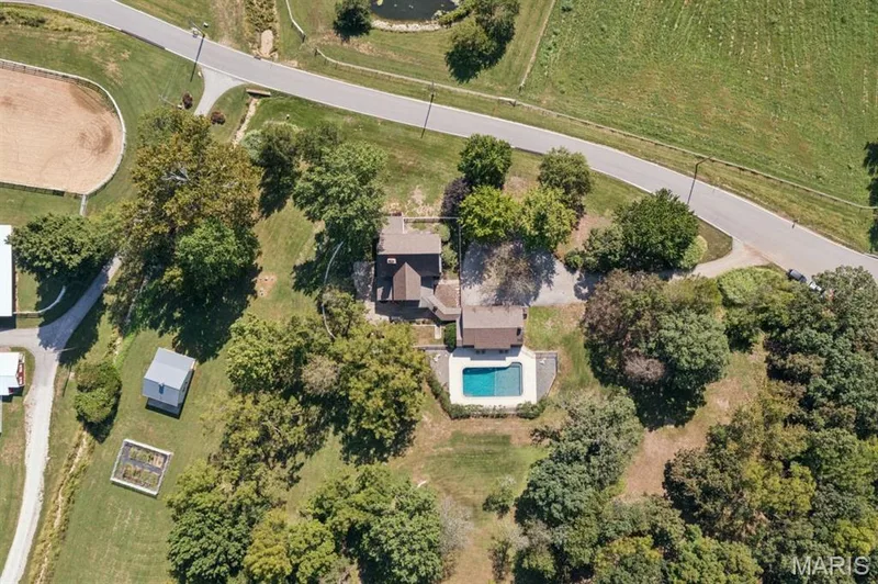Expansive property featuring a residence with a brown roof, a swimming pool with a surrounding paved deck, and a detached shed — 2333 Ossenfort Road, Wildwood, MO 63038