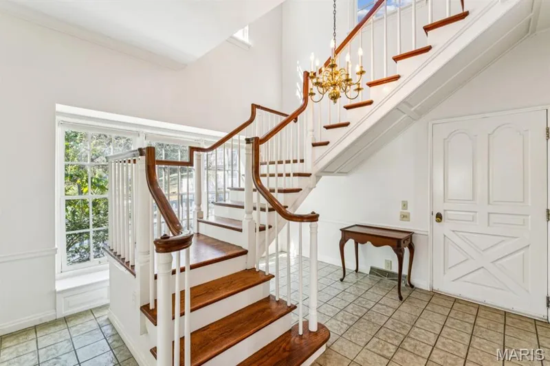 Tiled flooring entryway with a grand staircase featuring wood-finish treads and white risers — 2333 Ossenfort Road, Wildwood, MO 63038