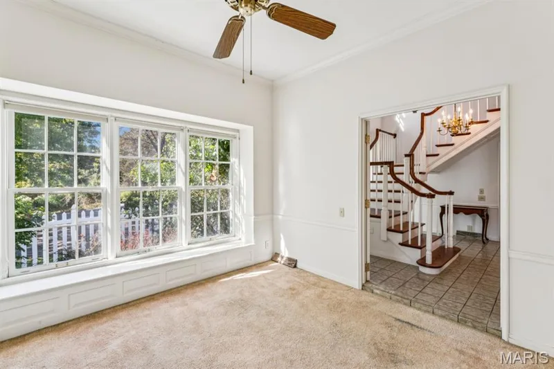 Triple bay window with integrated window seat, crown molding, ceiling fan, and staircase with wood railing and tile flooring — 2333 Ossenfort Road, Wildwood, MO 63038