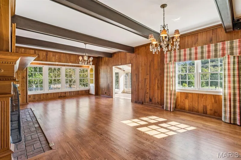 Hardwood flooring, wood paneling, exposed ceiling beams, brick fireplace, and multiple windows — 2333 Ossenfort Road, Wildwood, MO 63038