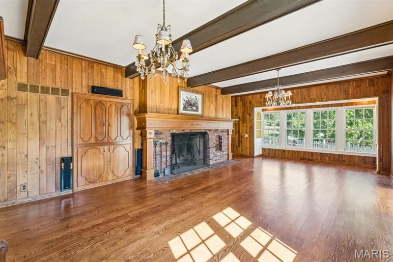 Hardwood flooring, wood-paneled walls, exposed ceiling beams, brick-surround fireplace with wood mantel, and multi-pane windows — 2333 Ossenfort Road, Wildwood, MO 63038