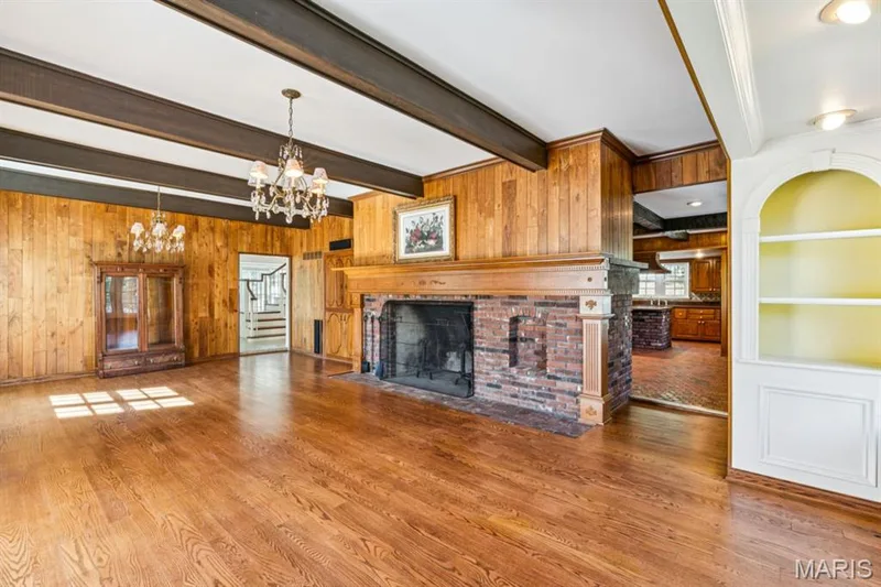 Hardwood flooring, double-sided brick fireplace with wood mantel, wood paneling, exposed ceiling beams, and built-in shelving — 2333 Ossenfort Road, Wildwood, MO 63038