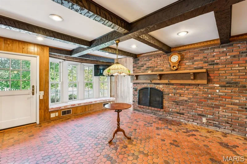 Brick accent wall with a built-in fireplace, exposed ceiling beams, a window bank with a built-in bench, and wood-finish paneling — 2333 Ossenfort Road, Wildwood, MO 63038