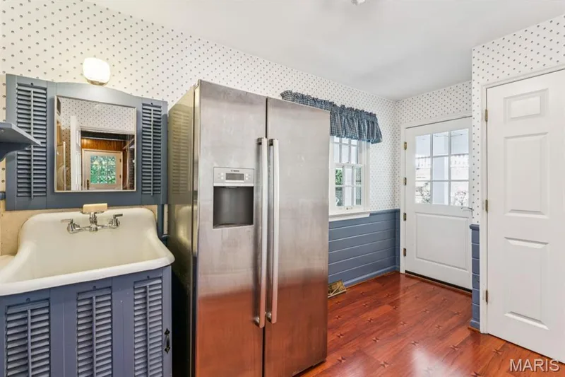 Stainless steel refrigerator, white utility sink, wood-finish flooring, white paneled door, and a white grid-patterned door — 2333 Ossenfort Road, Wildwood, MO 63038