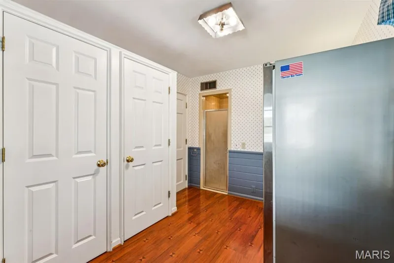 Wood-finish flooring, white paneled doors with brass hardware, and a ceiling-mounted light fixture — 2333 Ossenfort Road, Wildwood, MO 63038