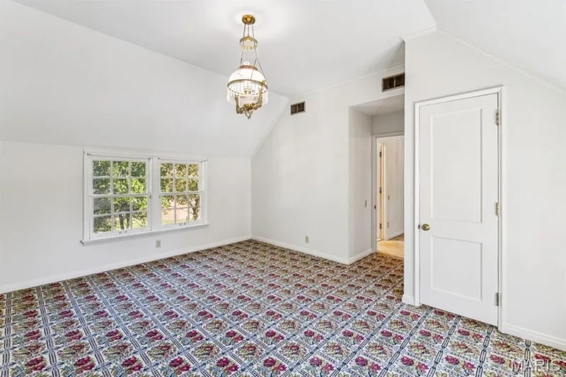 Windowed room featuring vaulted ceilings, a decorative chandelier, and patterned carpeting — 2333 Ossenfort Road, Wildwood, MO 63038