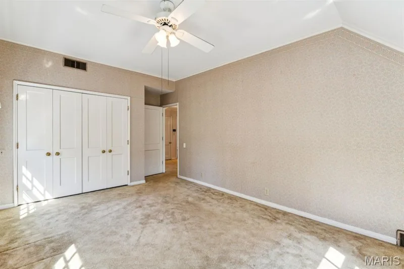 Patterned wall coverings, ceiling fan with light fixture, white bi-fold closet doors with brass hardware, and plush carpeting — 2333 Ossenfort Road, Wildwood, MO 63038