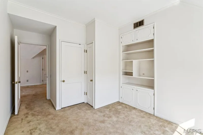 Built-in shelving with lower cabinetry, white painted doors with brass-toned hardware, and crown molding — 2333 Ossenfort Road, Wildwood, MO 63038