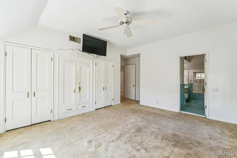 Vaulted ceiling with a ceiling fan, light-toned carpeting, white bi-fold closet doors, and an ornate built-in cabinet — 2333 Ossenfort Road, Wildwood, MO 63038