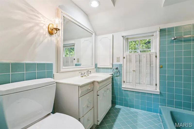 Bathroom featuring vibrant blue square tile, white vanity with integrated sink, white cabinetry, shuttered window, and recessed ceiling light — 2333 Ossenfort Road, Wildwood, MO 63038