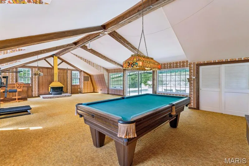 Vaulted ceilings with exposed wood beams, retro fireplace, and expansive windows overlook the salt-water pool. Pool table stays! — 2333 Ossenfort Road, Wildwood, MO 63038