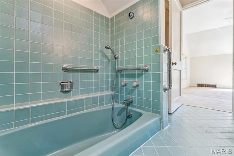 Bathroom featuring tiled walls, a built-in bathtub, a showerhead with a handheld sprayer, and chrome grab bars — 2333 Ossenfort Road, Wildwood, MO 63038