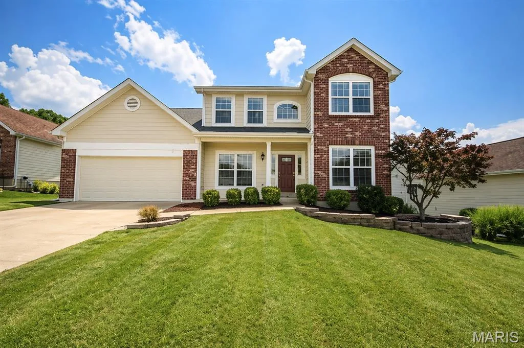 Two-story residence featuring brick and siding facade, a two-car garage, and an inviting front entry — 1126 Manor Cove Drive, St Charles, MO 63304
