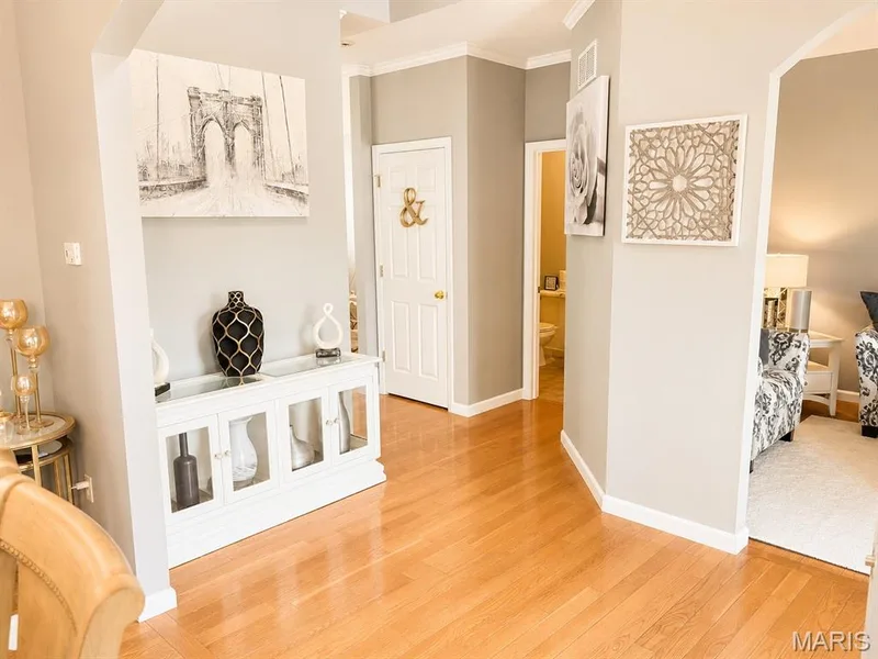 Hardwood flooring extends throughout this interior space, featuring a white built-in console cabinet with glass doors — 1126 Manor Cove Drive, St Charles, MO 63304
