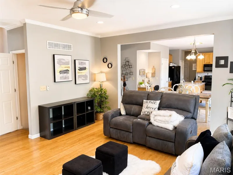 Open-concept living area with wood-finish flooring, crown molding, and a ceiling fan — 1126 Manor Cove Drive, St Charles, MO 63304