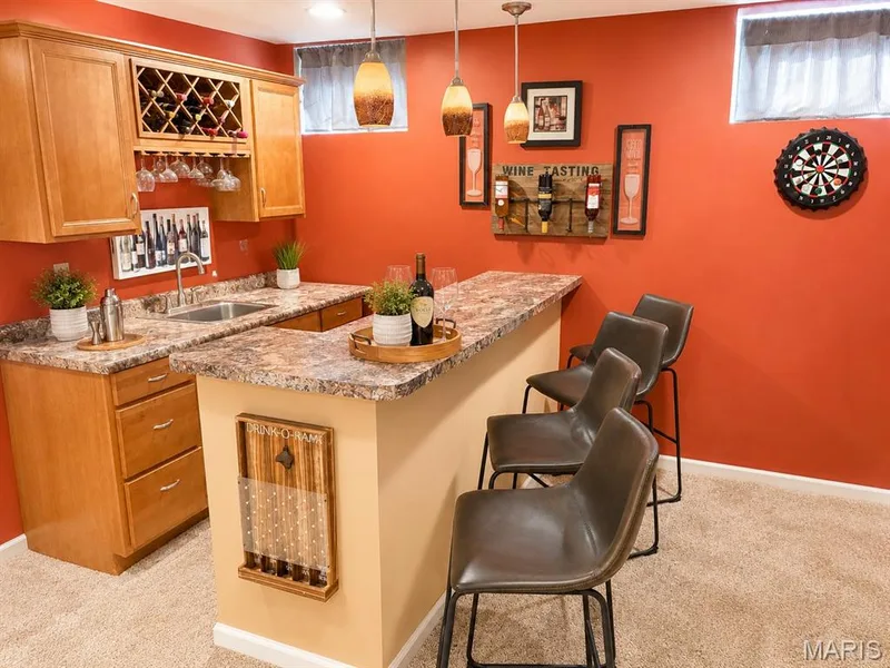 Custom wet bar featuring wood cabinetry, integrated wine rack, and a stainless steel sink — 1126 Manor Cove Drive, St Charles, MO 63304