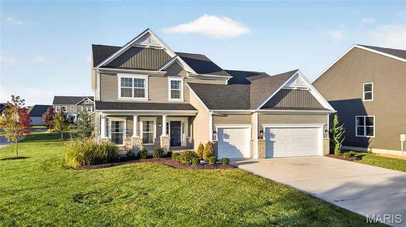 1.5-story siding exterior with stone accents, a covered front porch, and an attached three-car garage — 301 Healthy Way, St Charles, MO 63304