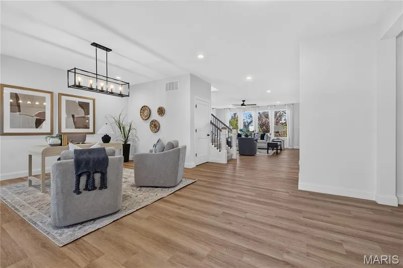 Luxury Vinyl Plank flooring throughout, a modern linear chandelier, recessed lighting, and a staircase with dark wood handrails — 301 Healthy Way, St Charles, MO 63304