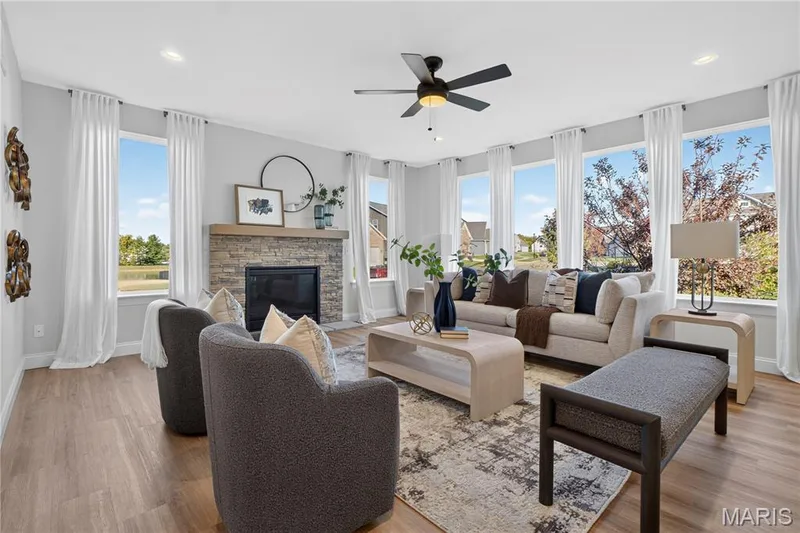 Spacious great room with a striking fireplace and an adjacent staircase accented by iron balusters. — 301 Healthy Way, St Charles, MO 63304
