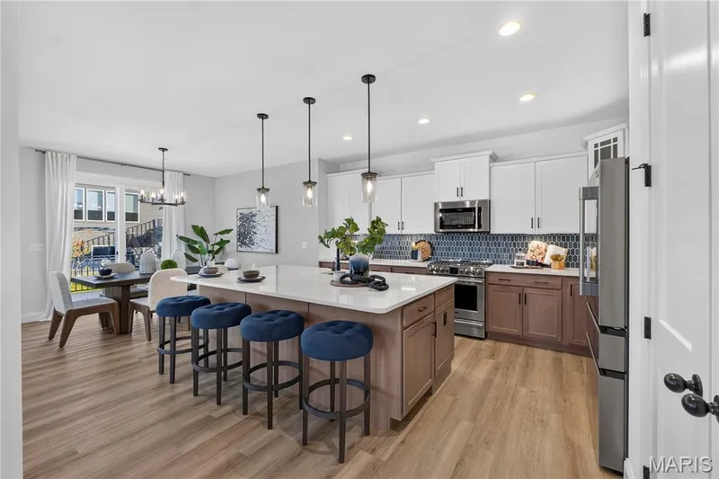 Oversized island with breakfast bar seating and pendant lighting creates an inviting gathering space. — 301 Healthy Way, St Charles, MO 63304