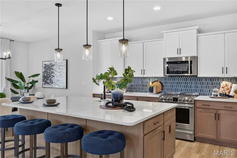 White upper cabinets pair with warm wood-tone lower cabinets and a striking blue tile backsplash. — 301 Healthy Way, St Charles, MO 63304