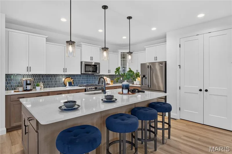 Oversized island with breakfast bar seating and pendant lighting creates an inviting gathering space. — 301 Healthy Way, St Charles, MO 63304